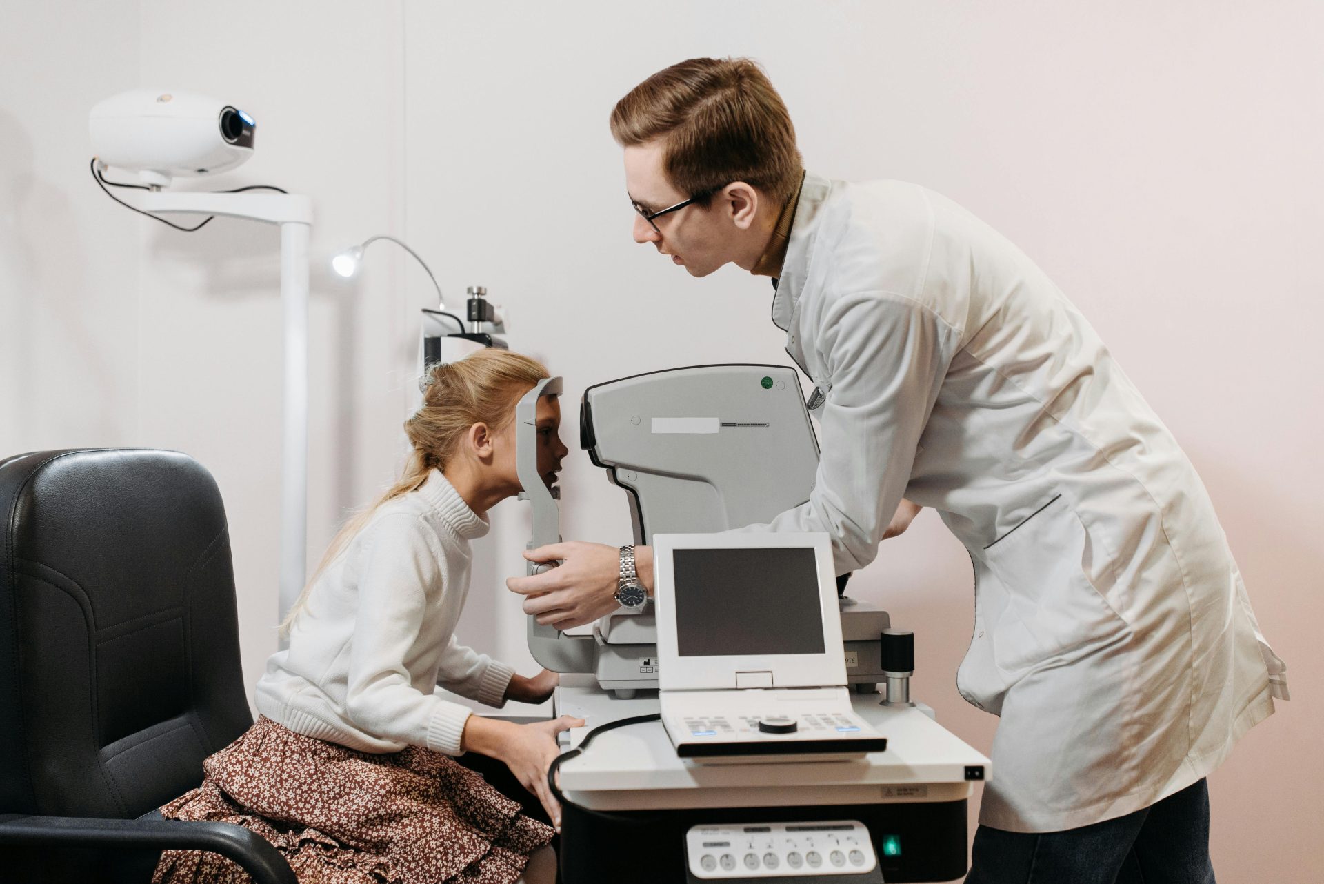 Junges Mädchen unterzieht sich in einer Klinik einer Augenuntersuchung bei einem Optiker mit medizinischen Geräten.
